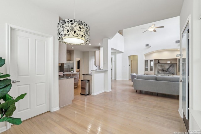 interior space featuring arched walkways, ceiling fan, visible vents, and light wood-style flooring