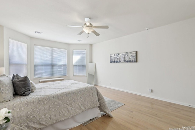 bedroom featuring light wood-type flooring, visible vents, ceiling fan, and baseboards