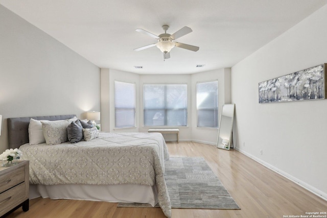 bedroom with a ceiling fan, light wood-type flooring, visible vents, and baseboards