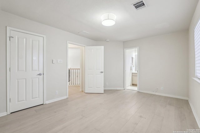 unfurnished bedroom featuring light wood-type flooring, visible vents, connected bathroom, and baseboards