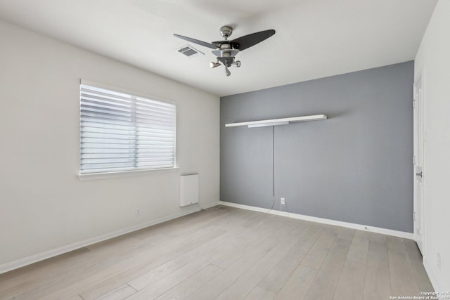 empty room featuring baseboards, ceiling fan, visible vents, and wood finished floors