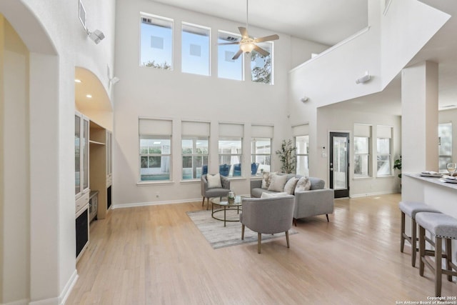 living room with ceiling fan, light wood-style flooring, and baseboards