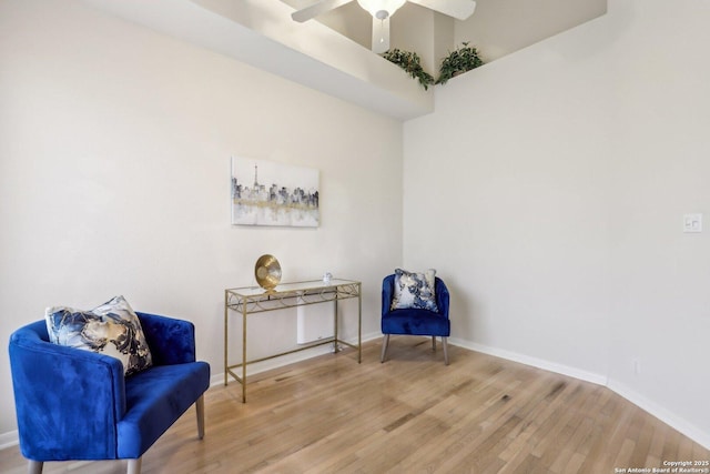 living area featuring ceiling fan, baseboards, and wood finished floors