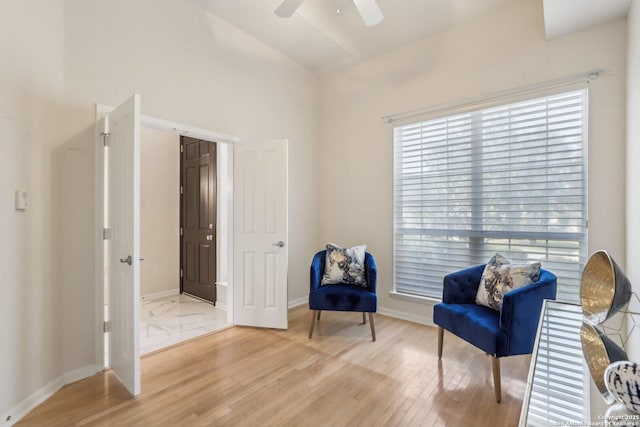 living area featuring ceiling fan, light wood finished floors, and baseboards