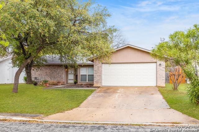 single story home featuring an attached garage, a front lawn, concrete driveway, and brick siding