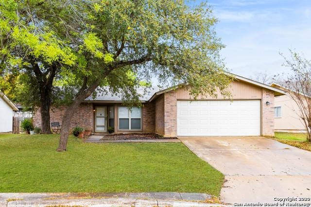 ranch-style home featuring a front yard, concrete driveway, brick siding, and an attached garage