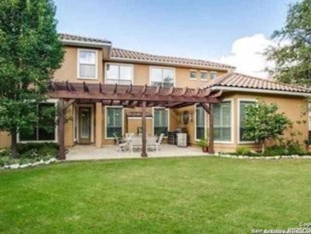 rear view of property featuring a lawn, a tile roof, a patio area, a pergola, and stucco siding