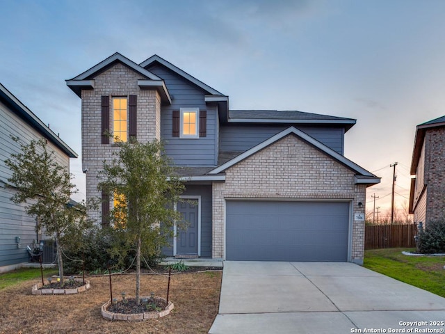 view of front of property featuring a garage, driveway, brick siding, and fence