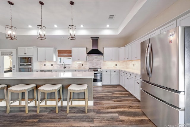 kitchen with stainless steel appliances, a sink, visible vents, decorative backsplash, and wall chimney exhaust hood