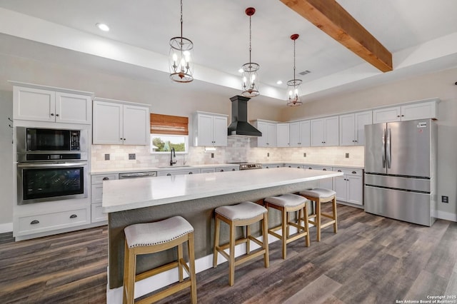 kitchen featuring tasteful backsplash, wall chimney exhaust hood, stainless steel appliances, and a sink