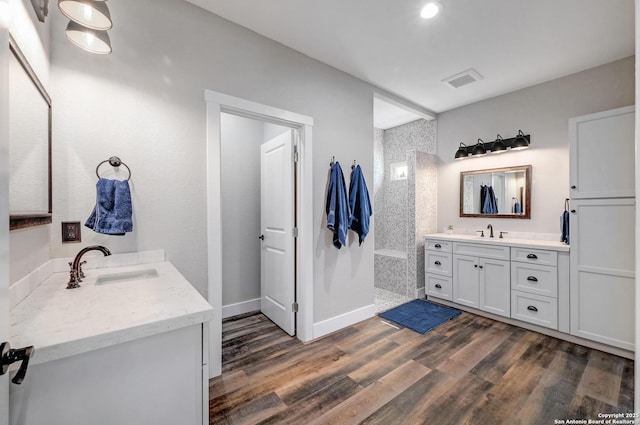 full bathroom with wood finished floors, two vanities, a sink, and visible vents