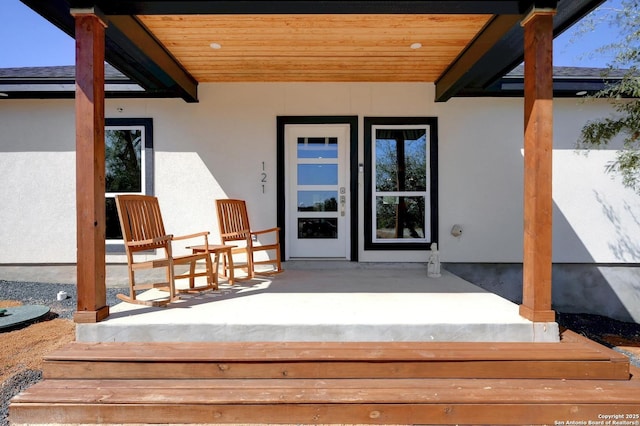 doorway to property with covered porch and stucco siding