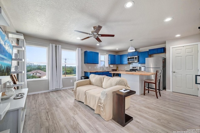 living room with light wood finished floors, baseboards, a textured ceiling, and recessed lighting