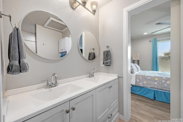 ensuite bathroom featuring a sink, double vanity, wood finished floors, and connected bathroom