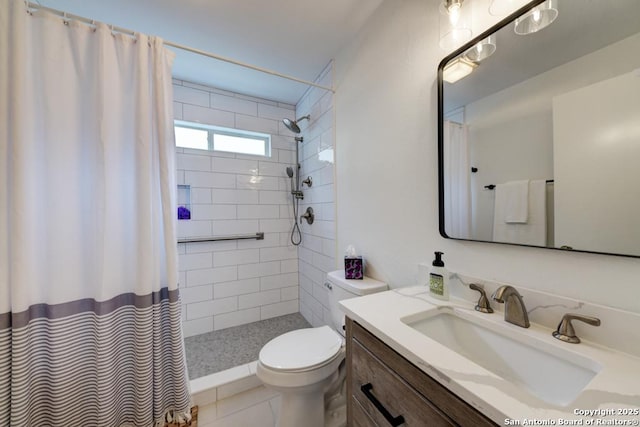 bathroom with a tile shower, vanity, toilet, and tile patterned floors