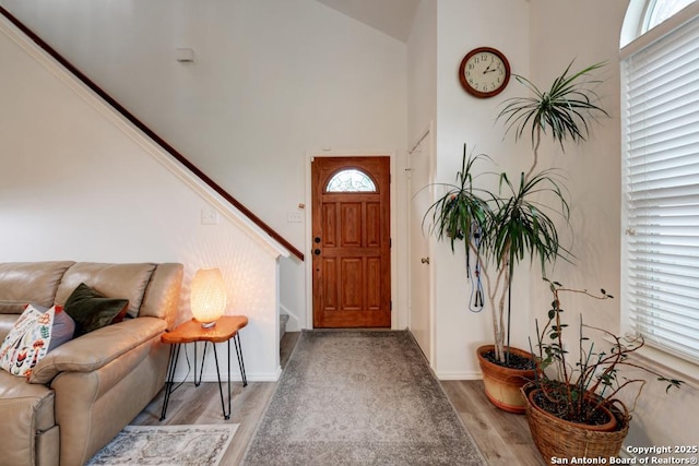 entryway featuring light wood-type flooring, a towering ceiling, and baseboards