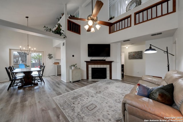 living area with visible vents, wood finished floors, and ceiling fan with notable chandelier