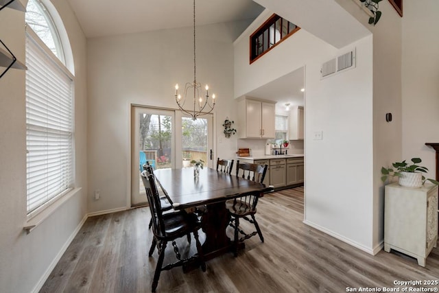 dining space with visible vents, a notable chandelier, baseboards, and wood finished floors