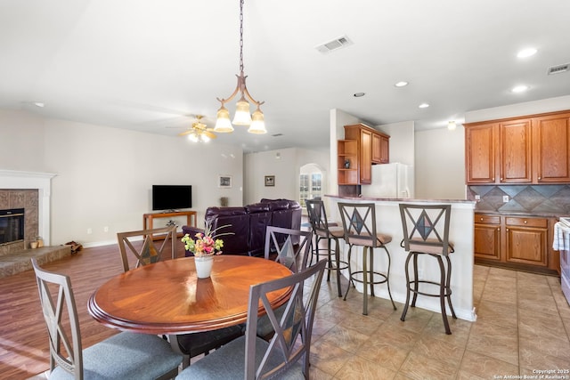 dining area with arched walkways, recessed lighting, visible vents, a premium fireplace, and baseboards