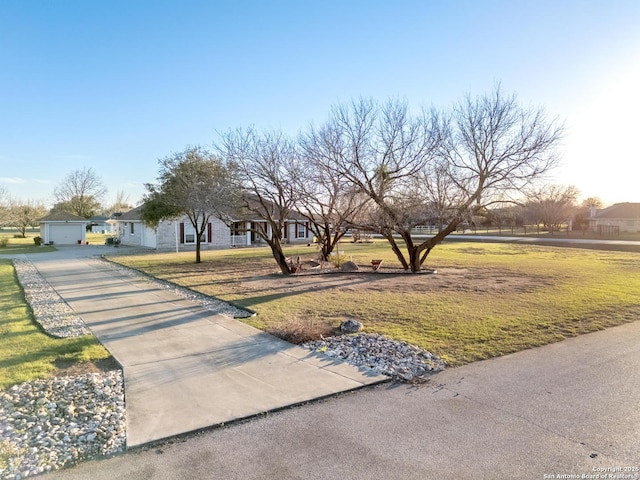 view of front facade with driveway, a garage, a front lawn, and an outdoor structure