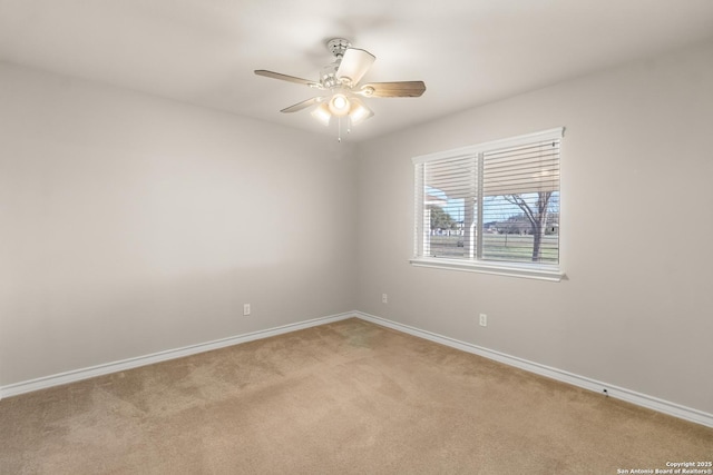 spare room with ceiling fan, baseboards, and light colored carpet