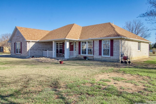 single story home with covered porch, brick siding, a front yard, and a shingled roof