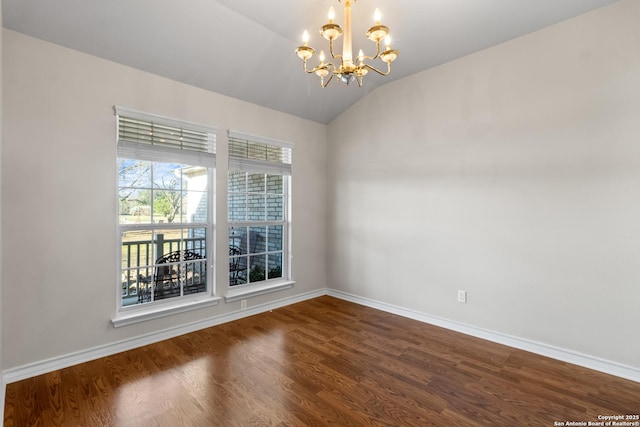 spare room featuring a notable chandelier, dark wood-type flooring, vaulted ceiling, and baseboards