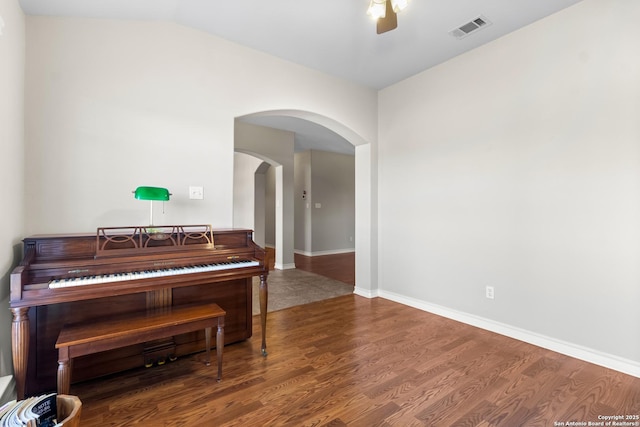 sitting room featuring baseboards, visible vents, a ceiling fan, arched walkways, and wood finished floors