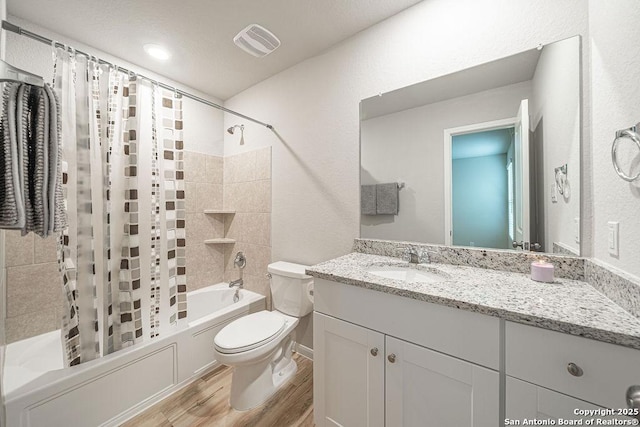 bathroom featuring visible vents, toilet, shower / bath combo with shower curtain, vanity, and wood finished floors