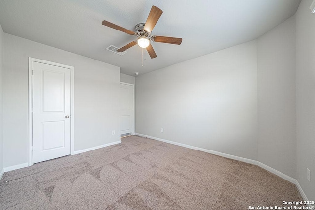 spare room with carpet floors, visible vents, ceiling fan, and baseboards