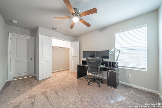 carpeted office space featuring visible vents, ceiling fan, and baseboards