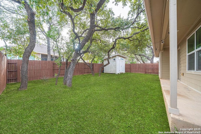 view of yard with a storage shed, a fenced backyard, and an outdoor structure