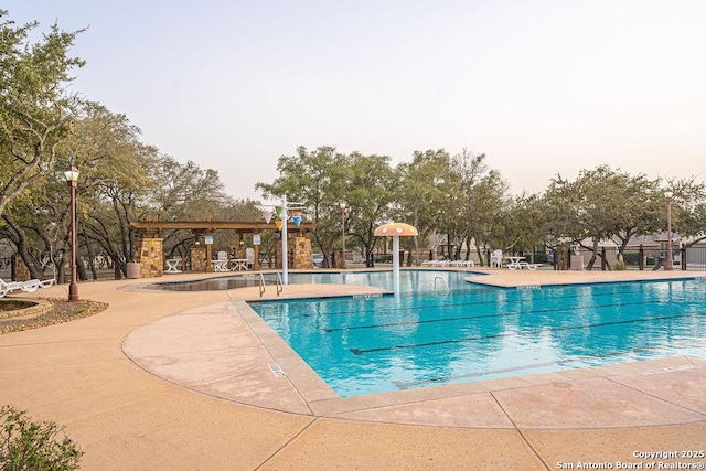 community pool with a patio and fence