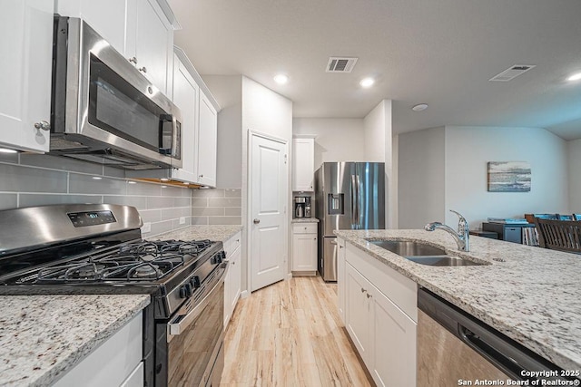 kitchen with a sink, visible vents, white cabinets, appliances with stainless steel finishes, and light wood-type flooring