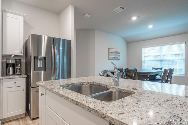 kitchen with visible vents, lofted ceiling, white cabinetry, stainless steel refrigerator with ice dispenser, and a sink