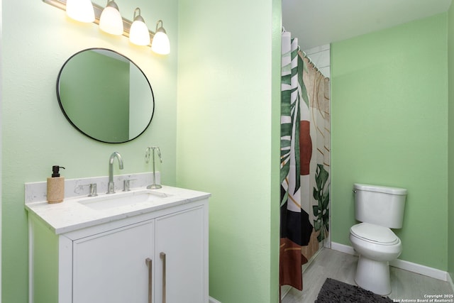 bathroom featuring wood finished floors, vanity, toilet, and baseboards