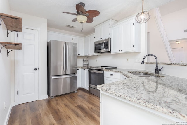 kitchen featuring light stone counters, visible vents, appliances with stainless steel finishes, dark wood-type flooring, and a sink