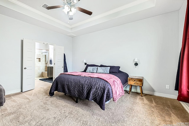 carpeted bedroom with ceiling fan, ensuite bathroom, baseboards, ornamental molding, and a tray ceiling