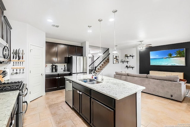 kitchen with light stone counters, stainless steel appliances, visible vents, a ceiling fan, and a sink