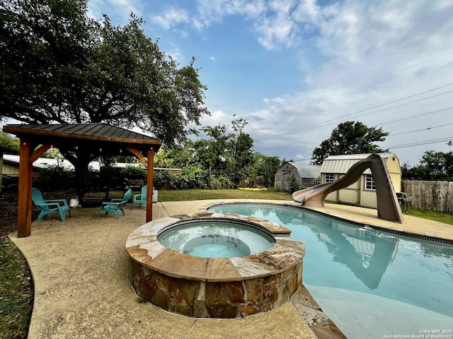 view of pool with a storage shed, a patio, a fenced backyard, a water slide, and a pool with connected hot tub