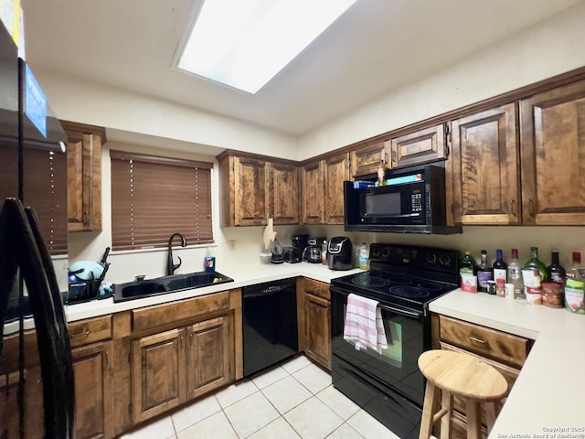 kitchen featuring light countertops, a sink, black appliances, and light tile patterned floors