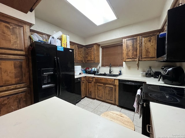 kitchen featuring light countertops, a sink, black appliances, and light tile patterned floors