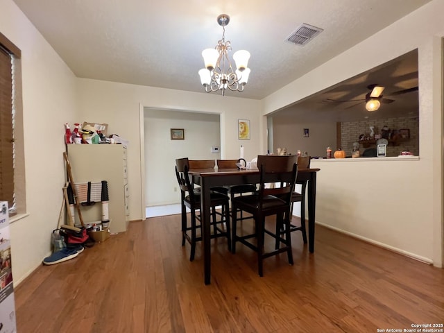 dining room with ceiling fan with notable chandelier, wood finished floors, and visible vents