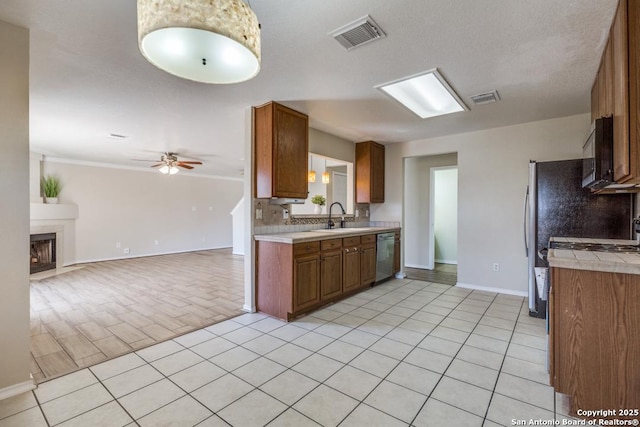 kitchen with a sink, visible vents, open floor plan, stainless steel dishwasher, and brown cabinets