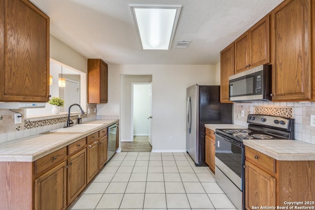 kitchen featuring appliances with stainless steel finishes, a sink, and brown cabinets