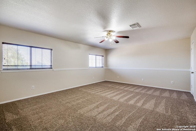 carpeted empty room featuring a textured ceiling, ceiling fan, visible vents, and baseboards