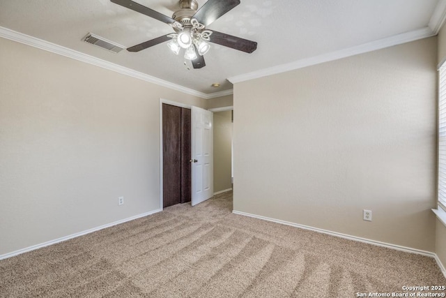 spare room featuring ceiling fan, carpet floors, visible vents, baseboards, and ornamental molding