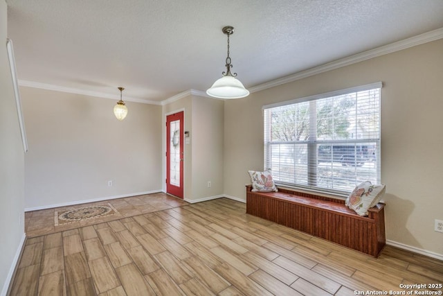 empty room featuring light wood-type flooring, a textured ceiling, baseboards, and crown molding