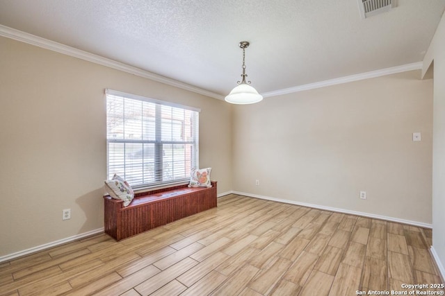 spare room featuring ornamental molding, light wood-style flooring, and visible vents