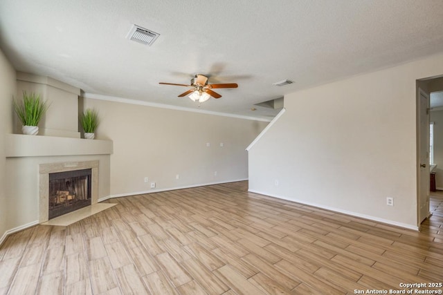 unfurnished living room featuring light wood-style flooring, a tiled fireplace, and visible vents